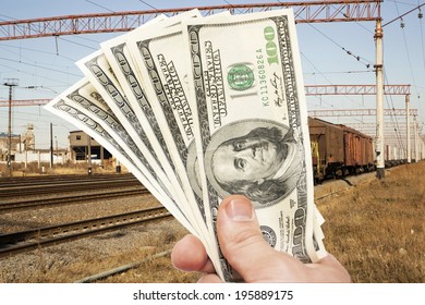 Man's Hand with notes of US dollars against the railroad