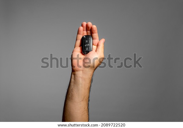 Man\'s hand offering in his flat the key to his\
car which he has for sale because it is a real disaster since it is\
always in the workshop