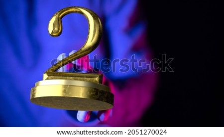 A man's hand on the background tapping on a 3d rendered golden 2 on a pedestal in blue neon light - anniversary and award concept