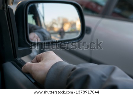 a man's hand on the car door on the background of a female silhouette in the mirror of the rear view mirror