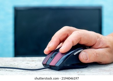 A Man's Hand On A Computer Mouse Near A Computer. Entering Data On A Computer Using A Mouse