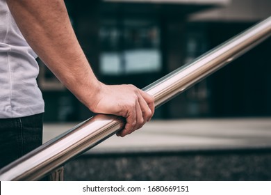 man's hand on the railing, a man in a white T-shirt and black jeans. go upstairs. outside