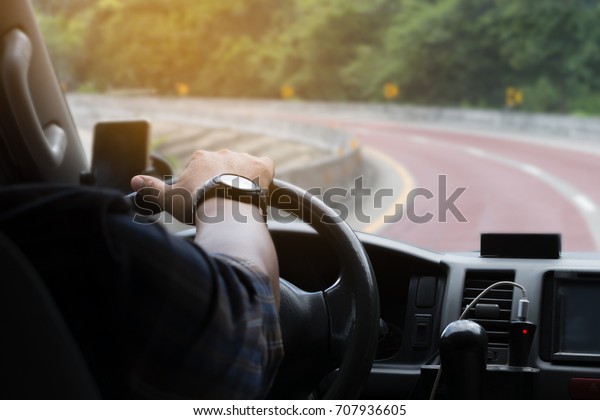 Man\'s hand on the steering wheel inside of a car,\
selective focus