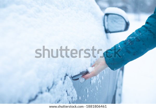 Man\'s hand opens the\
car door in winter