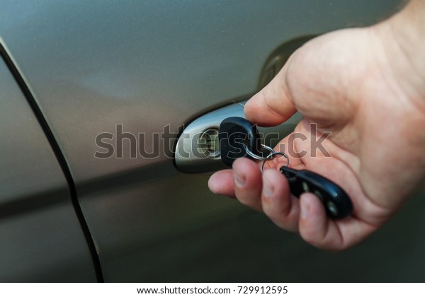 man\'s hand opens the\
car door with a key.