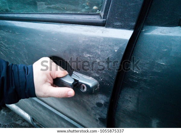 A man's hand opens
the door of the car.