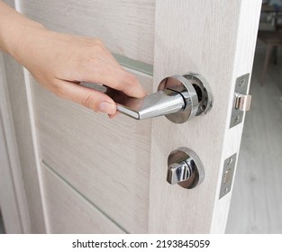 A man's hand opens an interior door with a broken doorknob. Poor quality door hardware, breakage, damage. Close-up - Shutterstock ID 2193845059