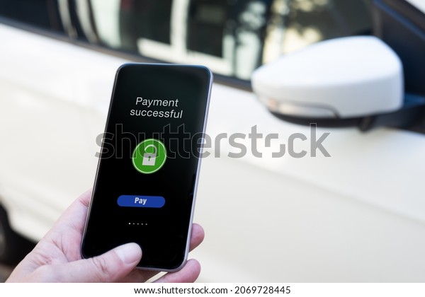 Man\'s hand pays for car rental with application on\
his phone with copy space