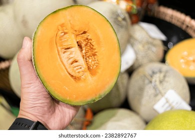 man's hand picking a melon from the supermarket basket. sliced cantaloupe melon. 