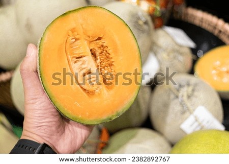 man's hand picking a melon from the supermarket basket. sliced cantaloupe melon. 