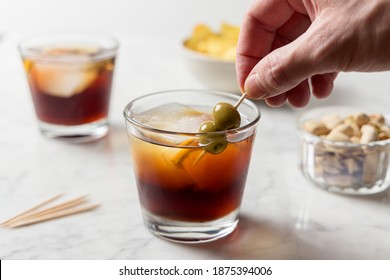 Man's Hand Picking Olives From Red Vermouth