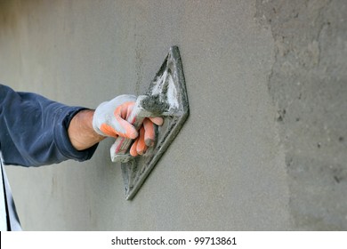 Man's hand plastering a wall with trowel. Construction worker.
Masonry tool. Construction industry. Selective focus.