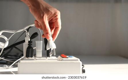 Man's hand is plugging the electrical plug into the socket. carefully