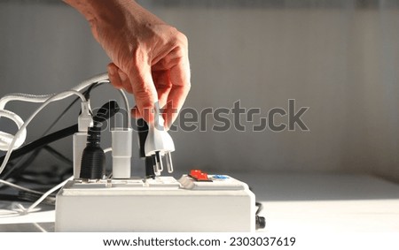 Man's hand is plugging the electrical plug into the socket. carefully