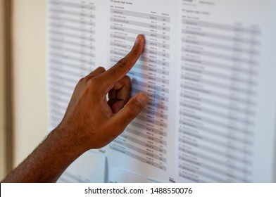 Man's hand pointing to a name list, trying to find some name