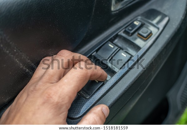 A man\'s hand presses\
the car door lock button to lock and unlock the car door from the\
inside close-up