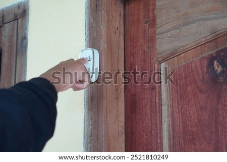 a man's hand presses the doorbell button in a house