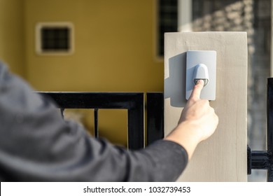Man's Hand Pressing A Doorbell Button With Sunlight. Close Up Hand And Finger Visiter Ringing Buzzer Doorbell. Guest Press Bell Behind Front Door Home.
