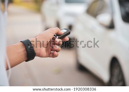 Man's hand pressing on the white car remote key
