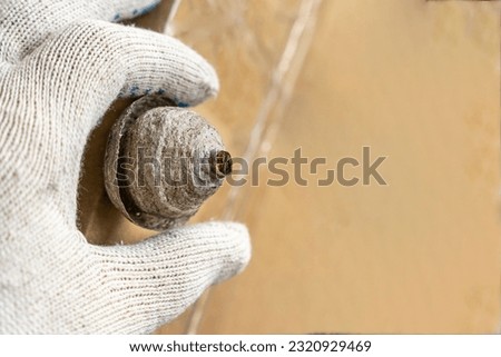 a man's hand in a protective work glove removes a wasps nest from his balcony. Danger or adrenaline. The threat of a wasp bite. Destruction of the wasp nest. wasps