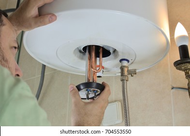 Man's Hand Putting A New Water Heater In A Boiler 