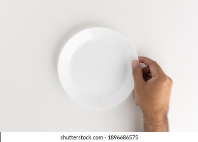 A Man's Hand Is Putting A White Empty Plate On The Table