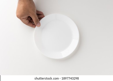 A Man's Hand Is Putting A White Empty Plate On The Table