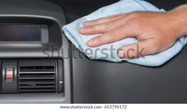 Man\'s hand with rag cleaning a car\
dashboard. Early spring cleaning or regular clean up.\
