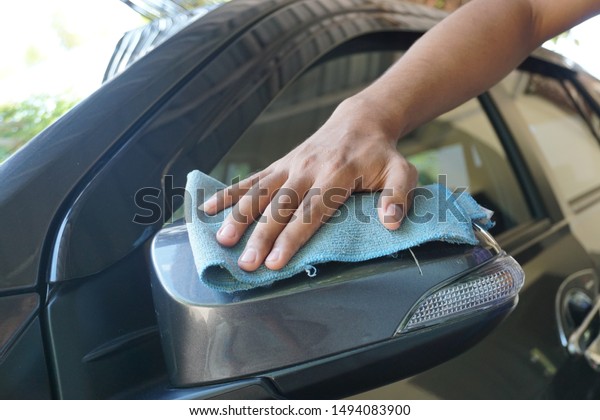 Man's
hand with rag cleaning a grey car's windshield . Early spring
washing or regular wash up. Professional car wash by hands. Hand
wipe cleaning the car with blue microfiber
cloth.