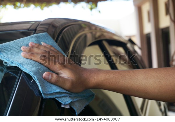 Man\'s\
hand with rag cleaning a grey car\'s windshield . Early spring\
washing or regular wash up. Professional car wash by hands. Hand\
wipe cleaning the car with blue microfiber\
cloth.