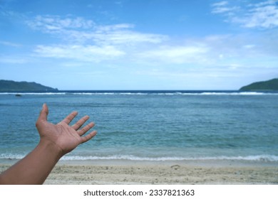 Man's hand reaching towards sea at beach - Powered by Shutterstock