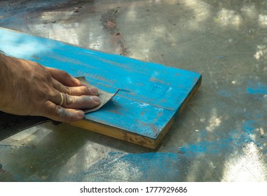 A Man's Hand With Sandpaper, Skinning An Old, Painted Board