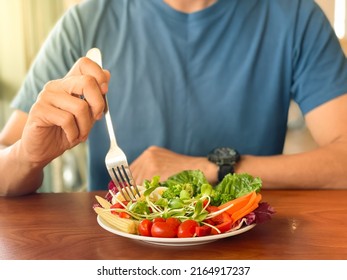 Man's hand scooping green salad. Healthy lifestyle and vegetarian vegan concept, Intermittent Fasting. - Shutterstock ID 2164917237