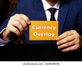 Man's hand showing orange business card with phrase Currency Overlay - closeup shot on grey background
 - Powered by Shutterstock