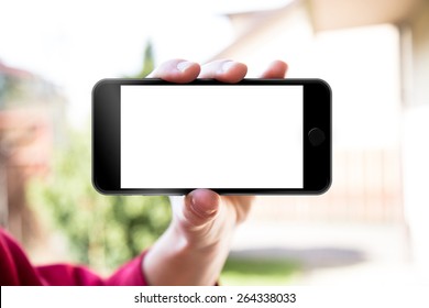 Man's Hand Shows Mobile Smartphone In Horizontal Position, Blurred Background - Mockup Template