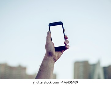 Man's Hand Shows Mobile Smartphone In Vertical Position, Blurred Background - Vintage Camera Roll Style Photo 