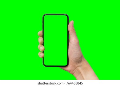 Man's hand shows mobile smartphone with green screen in vertical position isolated on green background. Mock up mobile