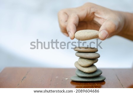 Man's hand stacking last stone over the table. Concept of meditation.