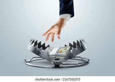A man's hand takes dollars from a bear trap. The concept of mortgage, dirty money, bribe, corruption, easy money, debt, credit. mixed media - Shutterstock ID 2167350373