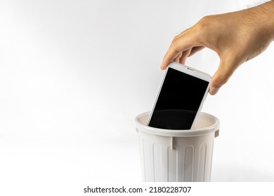 A man's hand throwing a smartphone in the trash. Image of digital detox