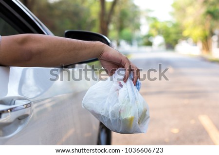 man's hand throwing trash out of car window, close up