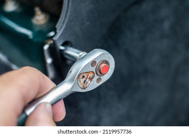 A man's hand tightens a bolt with a ratchet wrench. Selective focus, blurred background