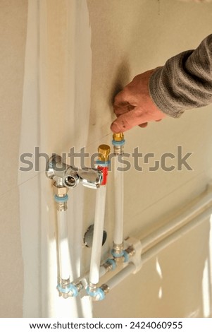 A man's hand tightens a fitting on a PER water inlet pipe attached to a plasterboard wall. Stok fotoğraf © 