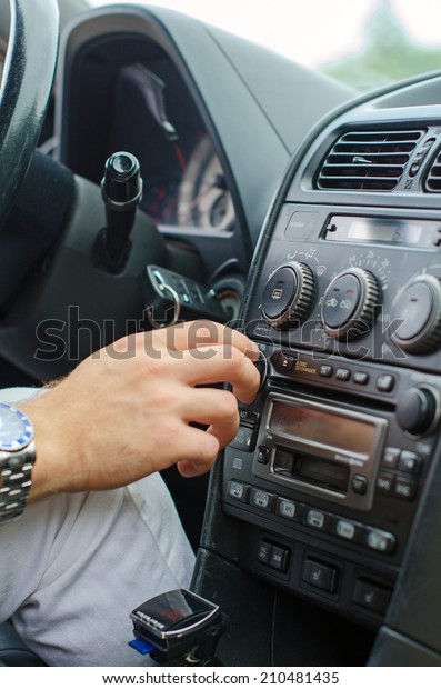Man\'s hand tuning radio in\
the car.
