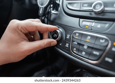 Man's hand turns the climate control wheel in a car. Temperature setting - Powered by Shutterstock