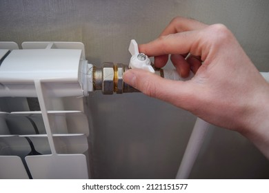 A Man's Hand Turns The Valve Of A Home Heating Radiator