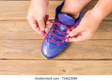 Man's Hand  Tying Laces Of Basketball Shoes Before Playing Basketball On Wooden Board