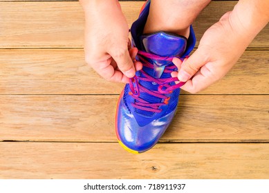 Man's Hand  Tying Laces Of Basketball Shoes Before Playing Basketball On Wooden Board