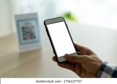 The Man's Hand Is Using A Mobile Phone To Scan QR Code. The Man Is Scanning To Use As A Discount For Food And Drink In The Restaurant Or Cafe. Pay Without Holding Cash.