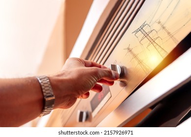 Man's hand using oven controls to prepare food fused with electricity towers. Concept of electrical energy use with household appliances.Selective focus - Shutterstock ID 2157926971